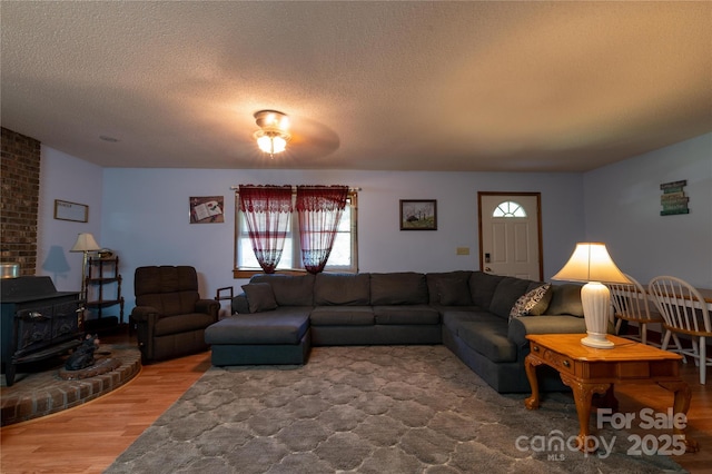 living room with hardwood / wood-style flooring, a textured ceiling, and a wood stove