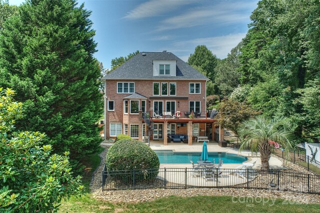 rear view of property featuring a patio, fence private yard, a balcony, brick siding, and a fenced in pool