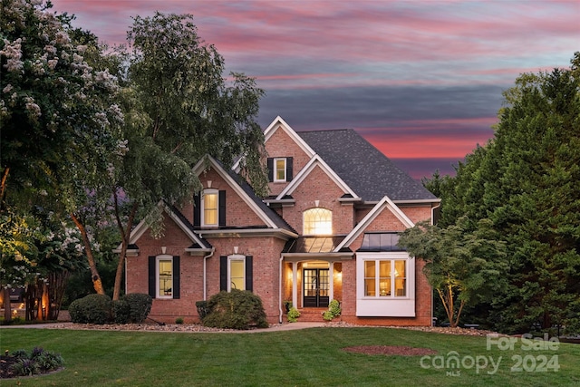 traditional-style home with brick siding, a shingled roof, and a yard