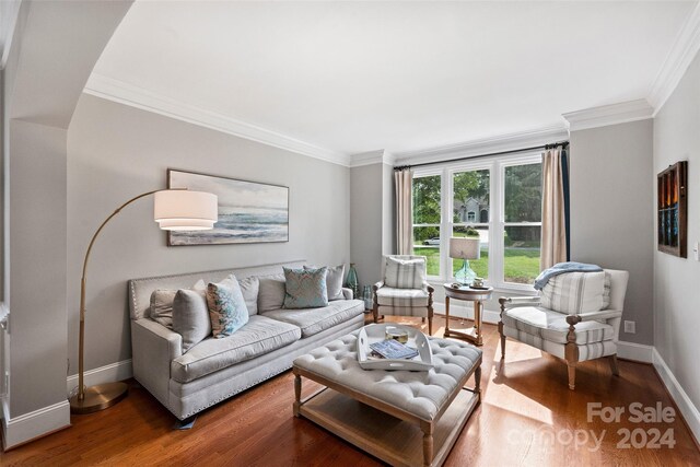 living area featuring ornamental molding, baseboards, and wood finished floors