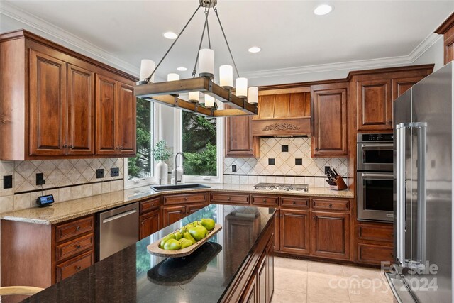 kitchen featuring light tile patterned floors, a sink, ornamental molding, appliances with stainless steel finishes, and dark stone countertops