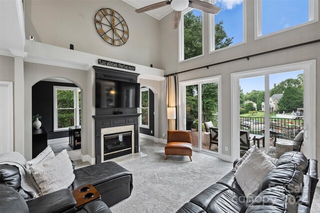 living area with a fireplace with flush hearth, arched walkways, a wealth of natural light, and carpet flooring