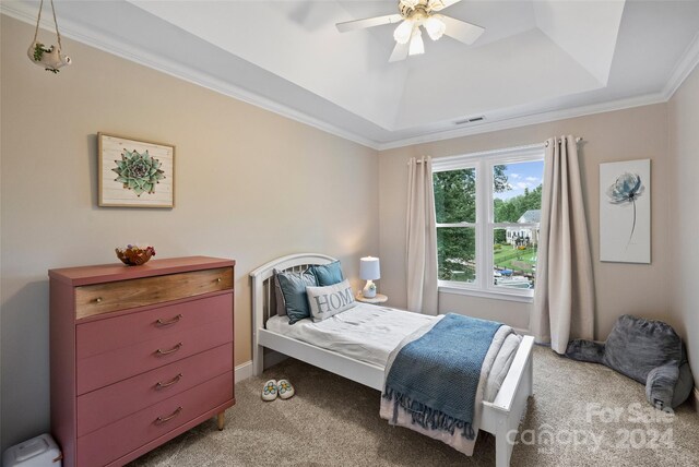 carpeted bedroom with a ceiling fan, a raised ceiling, visible vents, and crown molding