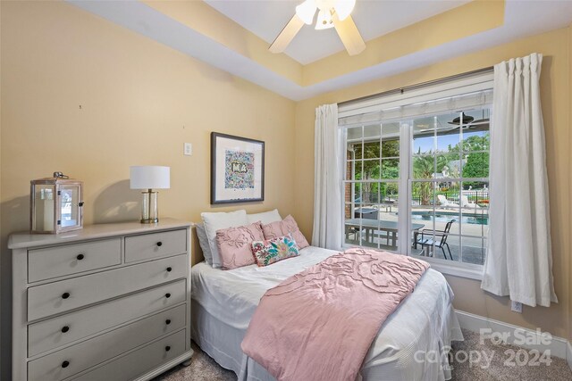 bedroom featuring a raised ceiling, ceiling fan, and baseboards