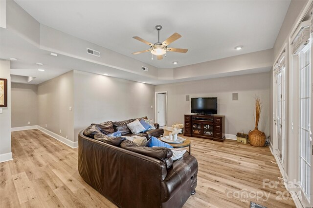 living area featuring light wood-style floors, visible vents, baseboards, and a ceiling fan