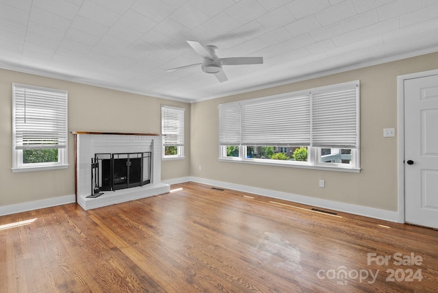 unfurnished living room featuring hardwood / wood-style floors, ceiling fan, a brick fireplace, and a healthy amount of sunlight