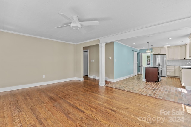 unfurnished living room featuring ornate columns, ceiling fan, ornamental molding, and light hardwood / wood-style flooring