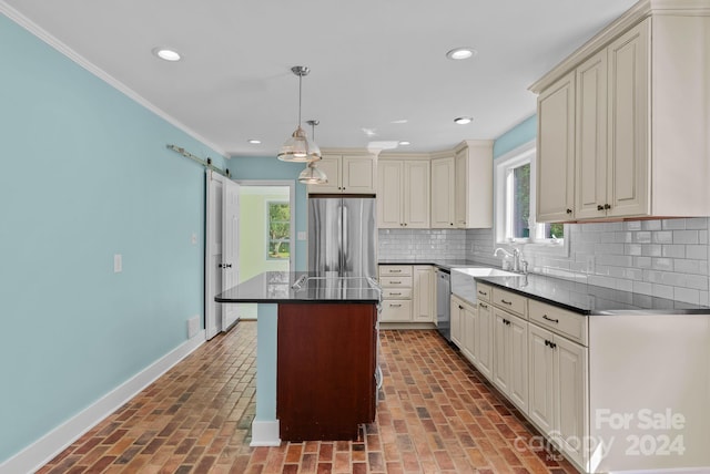 kitchen featuring backsplash, cream cabinets, a center island, a barn door, and stainless steel appliances