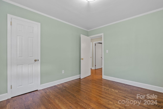 empty room featuring dark wood-type flooring and ornamental molding