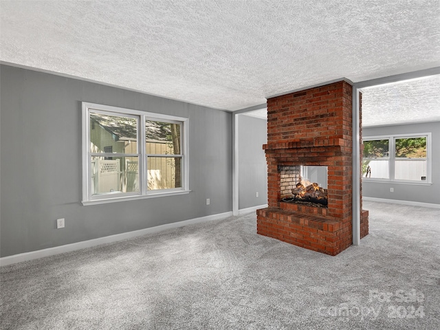 unfurnished living room with a fireplace, a textured ceiling, carpet floors, and brick wall