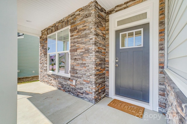 doorway to property with covered porch and stone siding