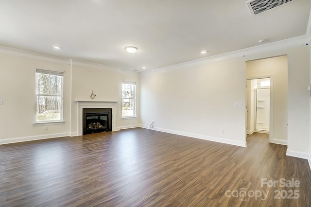 unfurnished living room with a fireplace, visible vents, baseboards, ornamental molding, and dark wood finished floors