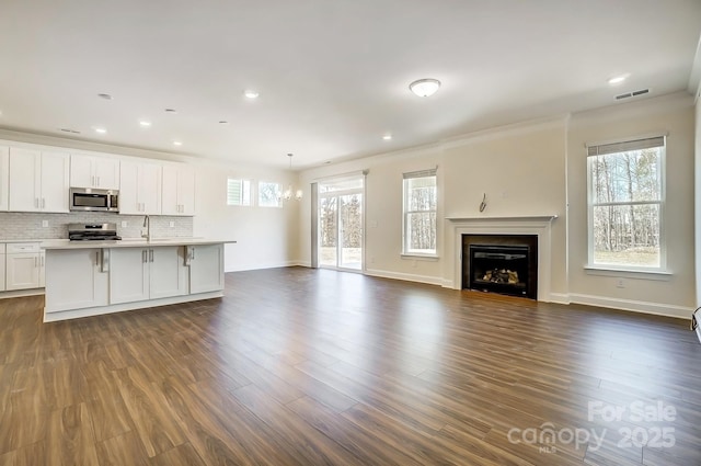 unfurnished living room with dark wood-type flooring, plenty of natural light, visible vents, and a fireplace