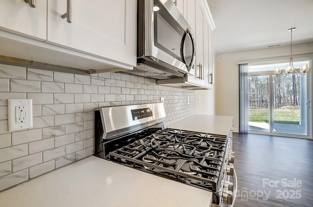 kitchen with decorative light fixtures, light countertops, decorative backsplash, appliances with stainless steel finishes, and white cabinetry