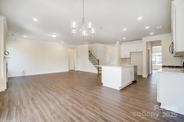 kitchen with open floor plan, wood finished floors, a sink, stainless steel appliances, and backsplash