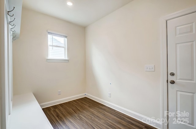 unfurnished room with baseboards and dark wood-type flooring