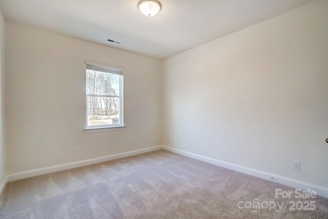 carpeted spare room with visible vents and baseboards