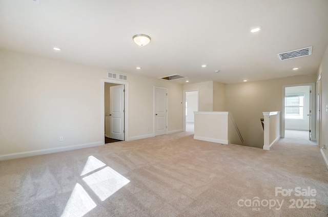 unfurnished room with light colored carpet, visible vents, baseboards, and recessed lighting