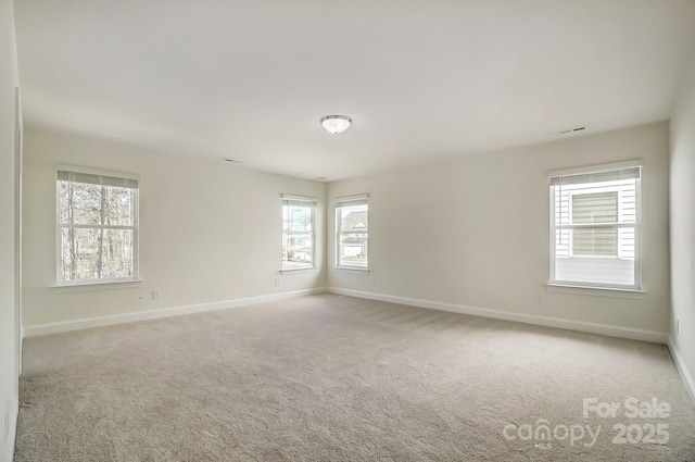 empty room with carpet flooring, visible vents, and baseboards