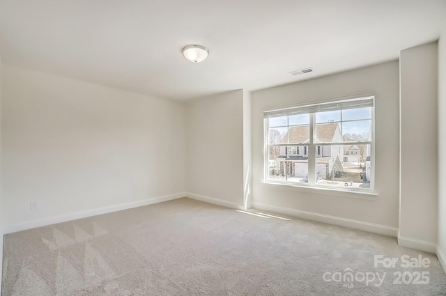 empty room with carpet, visible vents, and baseboards