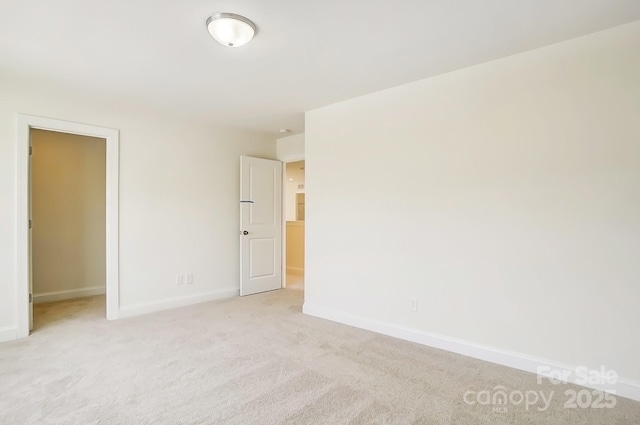 spare room with baseboards and light colored carpet