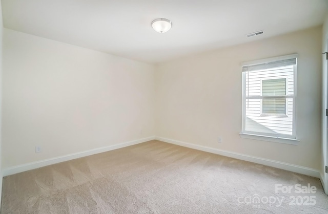 spare room featuring light carpet, visible vents, and baseboards