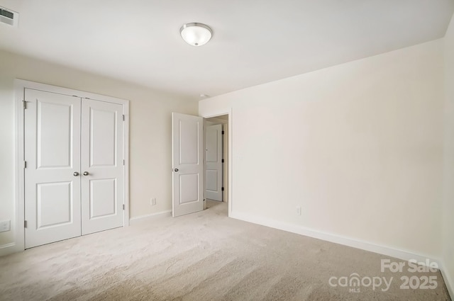 unfurnished bedroom featuring carpet floors, baseboards, and a closet