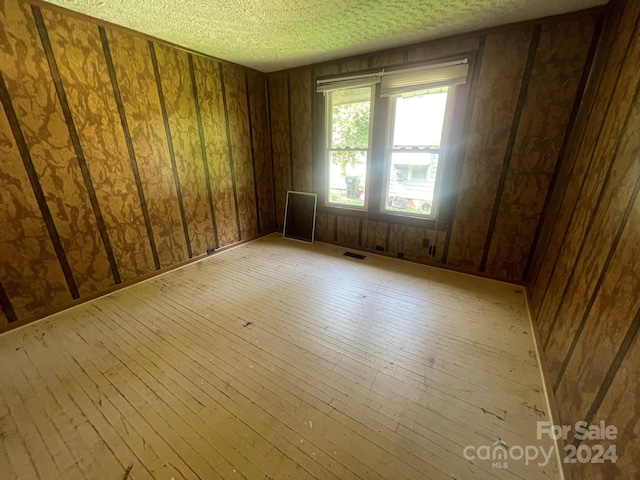 empty room featuring a textured ceiling and light wood-type flooring