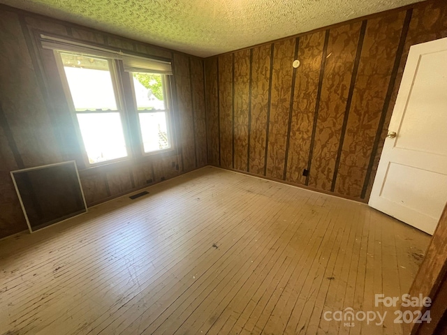 empty room featuring a textured ceiling and light wood-type flooring