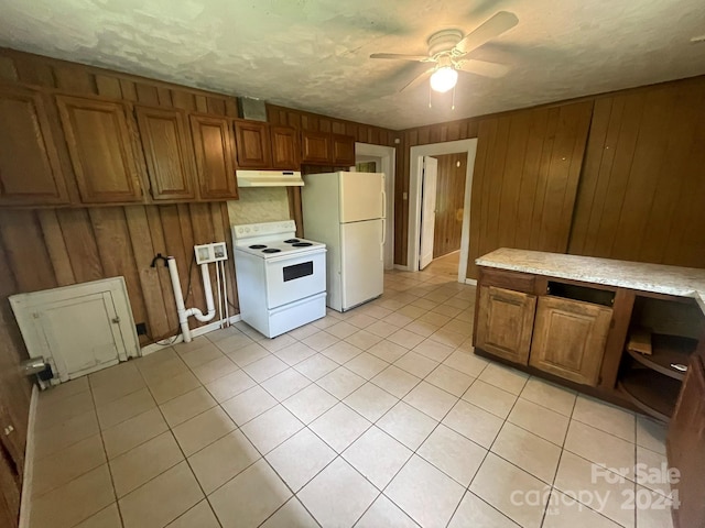 kitchen featuring ceiling fan, white appliances, light tile patterned floors, and wood walls