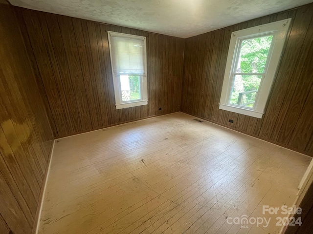 unfurnished room featuring light hardwood / wood-style flooring and wooden walls