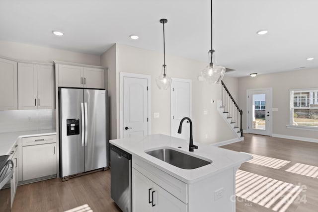 kitchen with stainless steel appliances, sink, hardwood / wood-style floors, white cabinetry, and an island with sink