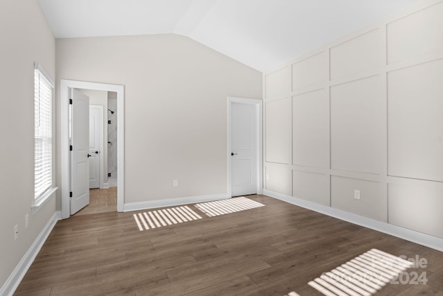 unfurnished bedroom featuring dark hardwood / wood-style flooring, lofted ceiling, and a closet