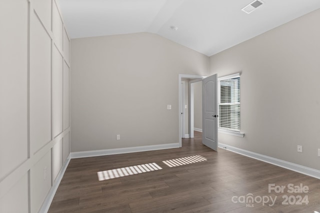 unfurnished bedroom with a closet, dark hardwood / wood-style flooring, and vaulted ceiling