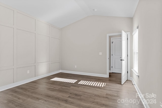 spare room featuring hardwood / wood-style floors and vaulted ceiling