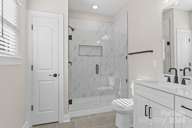 bathroom with tile patterned floors, vanity, a shower with shower door, and toilet