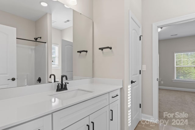 bathroom featuring tile patterned flooring, vanity, walk in shower, and a healthy amount of sunlight