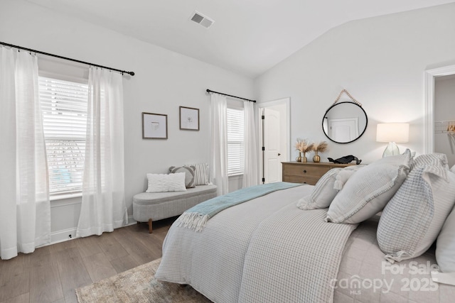 bedroom with wood-type flooring, vaulted ceiling, and multiple windows