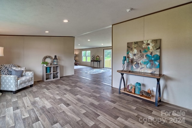 living area featuring hardwood / wood-style flooring, ornamental molding, and a textured ceiling