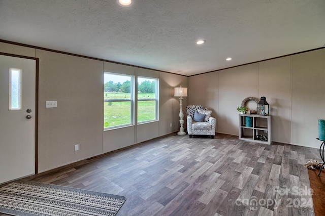 unfurnished room featuring a textured ceiling, crown molding, and hardwood / wood-style floors