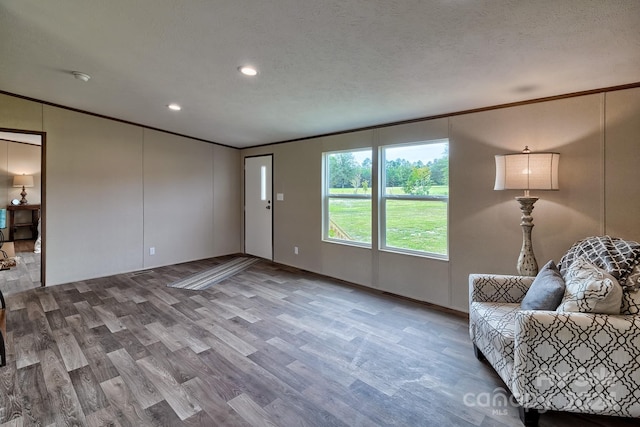 interior space with hardwood / wood-style flooring, ornamental molding, and a textured ceiling