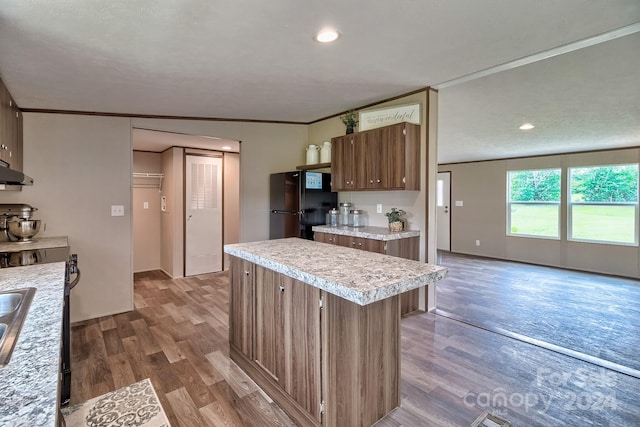 kitchen with crown molding, a center island, black fridge, and dark hardwood / wood-style flooring