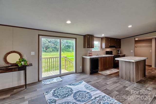 kitchen featuring light hardwood / wood-style floors, a center island, sink, black appliances, and dark brown cabinetry