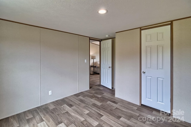 unfurnished bedroom with a closet, light wood-type flooring, and a textured ceiling