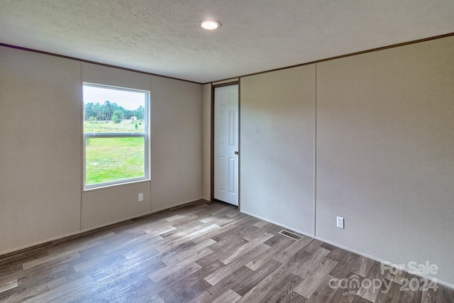 empty room with a textured ceiling and light hardwood / wood-style floors