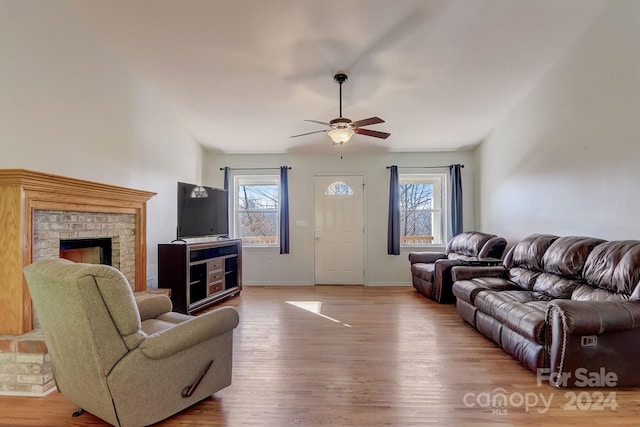 living room with ceiling fan, hardwood / wood-style flooring, and a brick fireplace