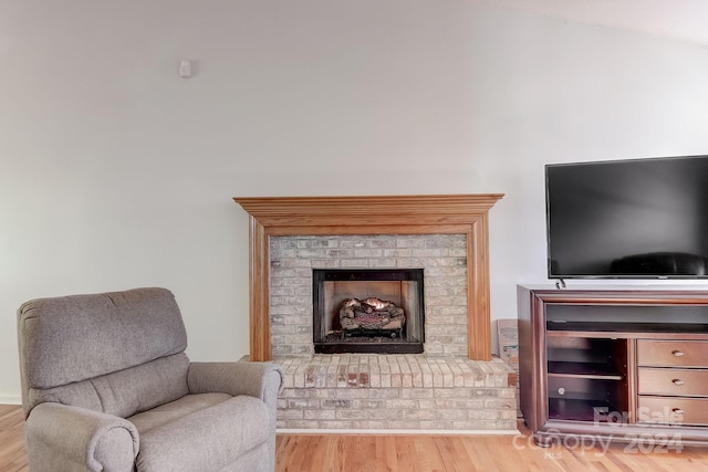 sitting room featuring light wood-type flooring and a brick fireplace