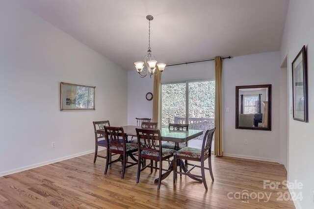 dining area featuring vaulted ceiling, an inviting chandelier, and light hardwood / wood-style floors