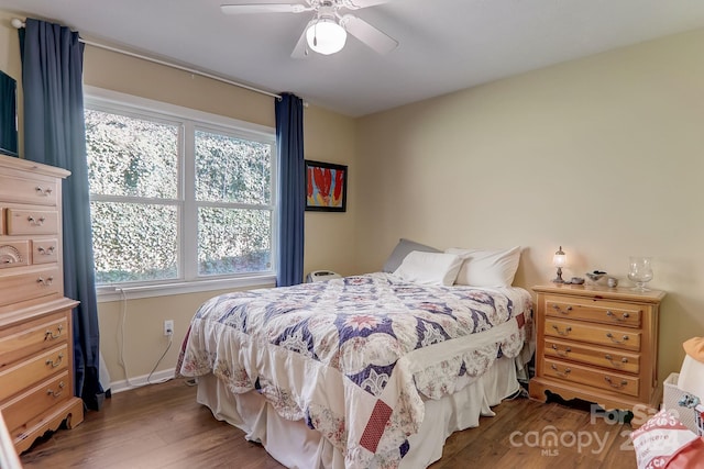 bedroom with ceiling fan, dark wood-type flooring, and multiple windows