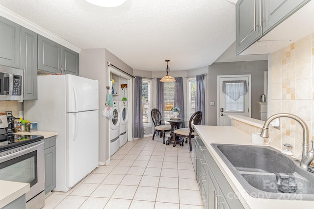 kitchen with stainless steel appliances, gray cabinets, washer and clothes dryer, and sink